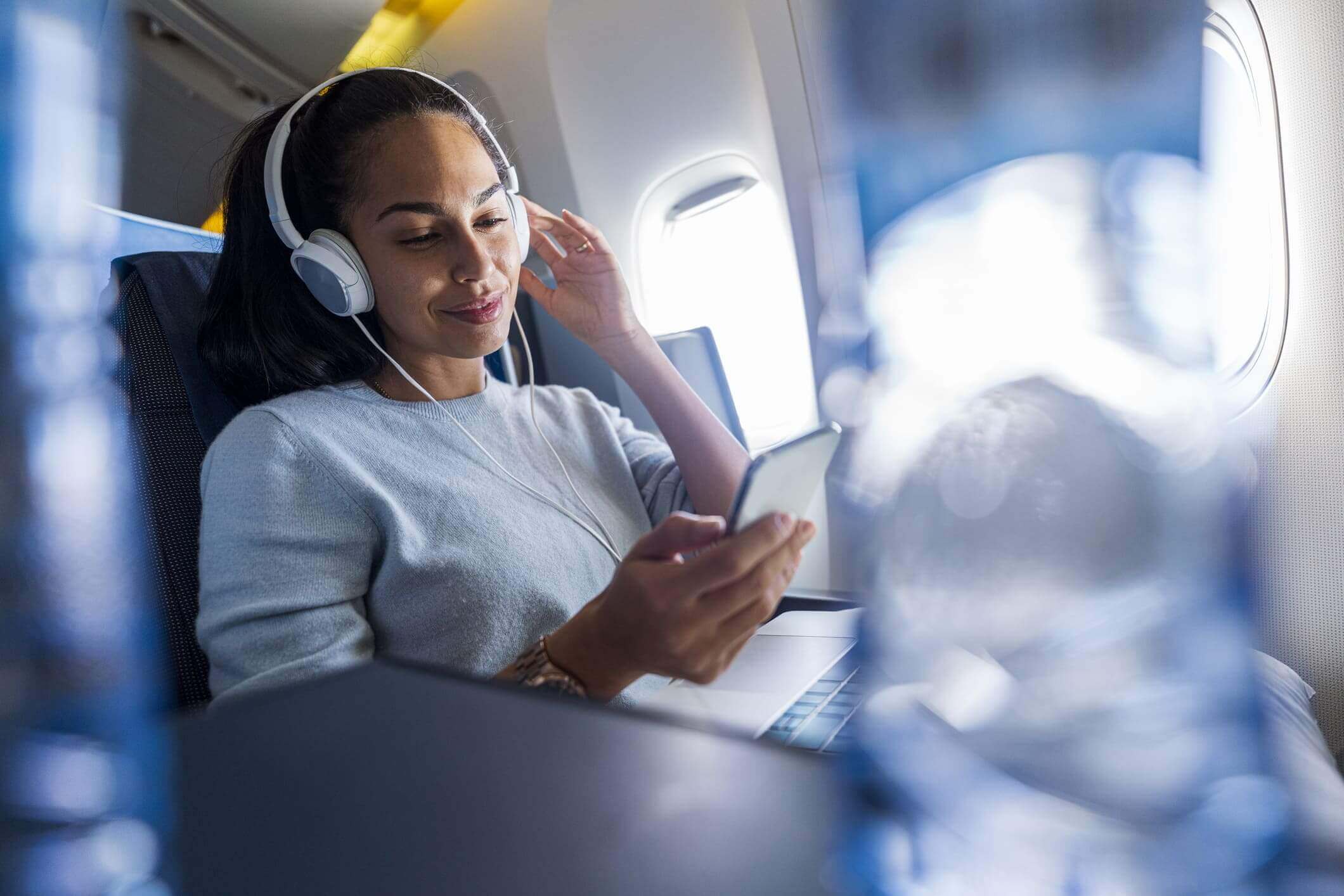 Woman with headphones on a plane smiling