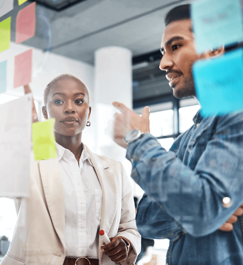 Two colleagues discussing incentive program design ideas with sticky notes