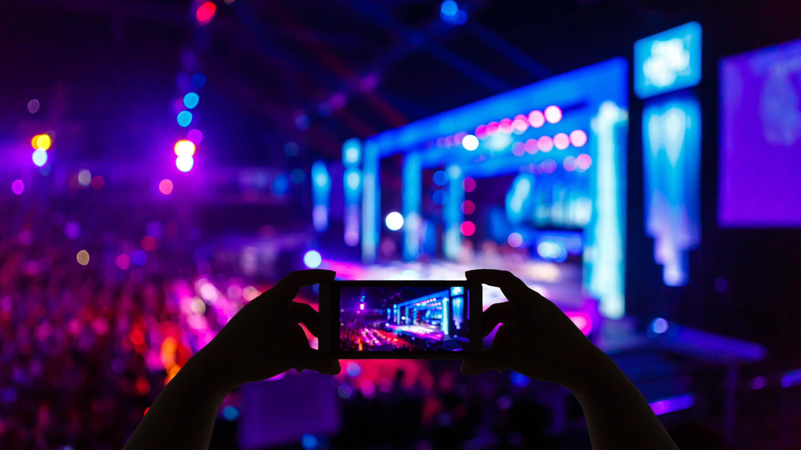 taking a photo of lit up pink, purple and blue stage