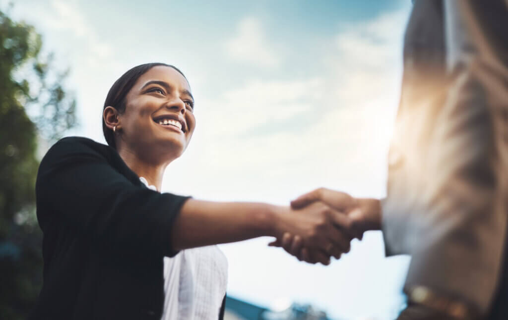 Woman extends her hand to shake with another business professional