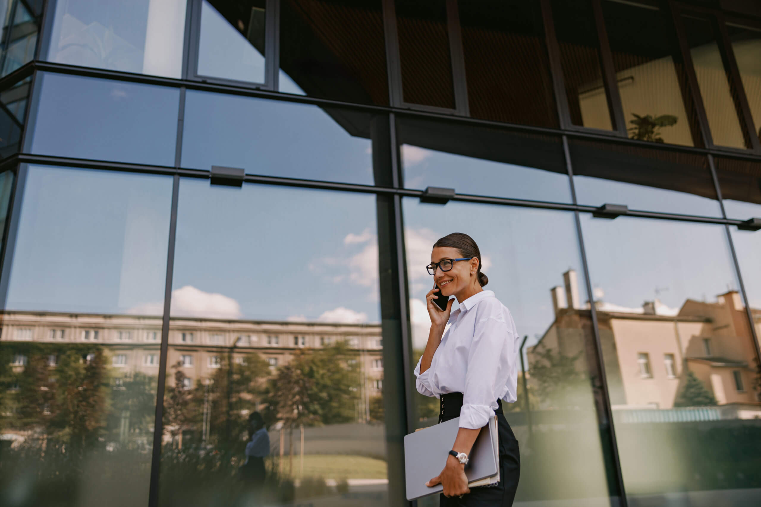 A Professional Woman Dressed in Business Attire Walks Confidently with Her Laptop