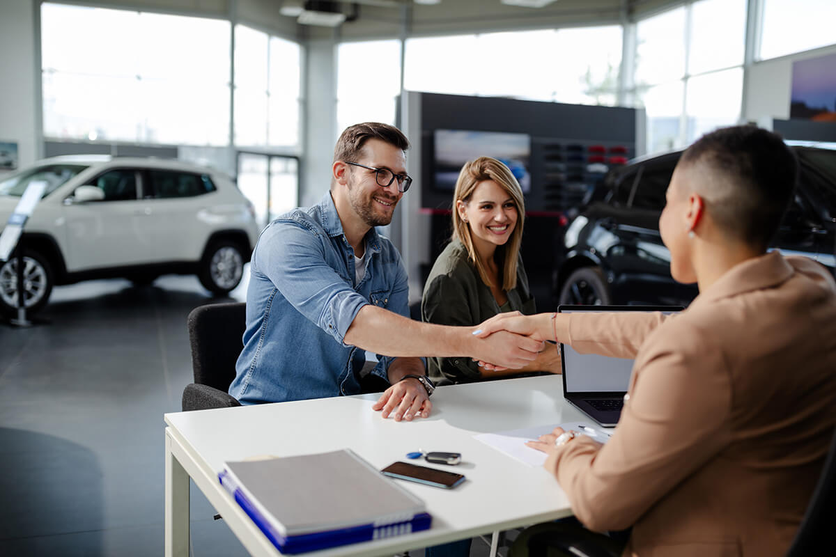 Smiling couple shaking hands with retail associate