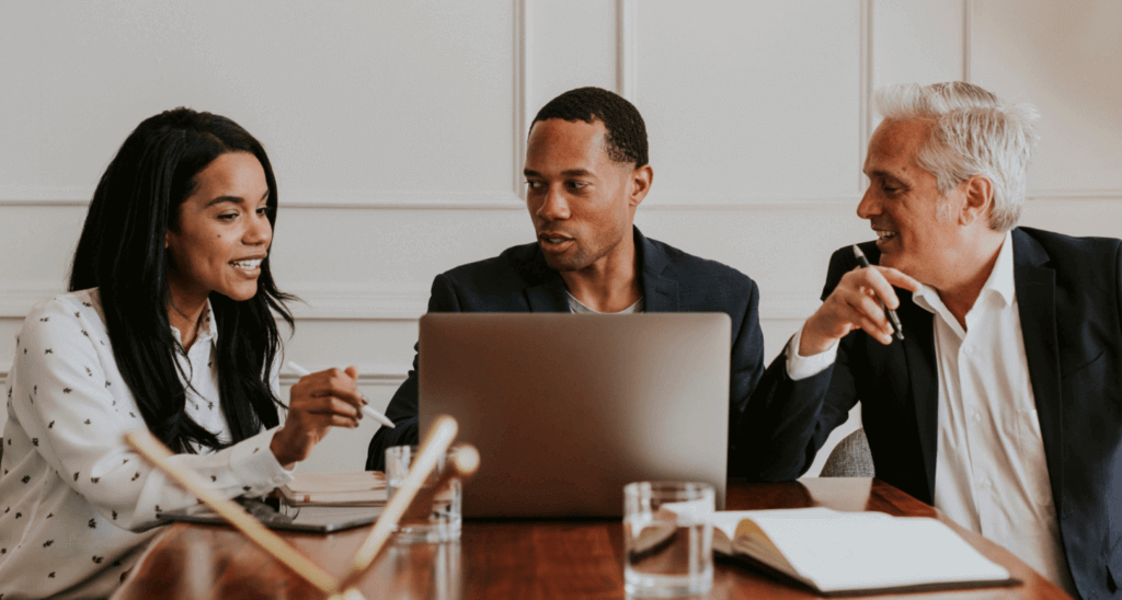 team of three people collaborating around a laptop