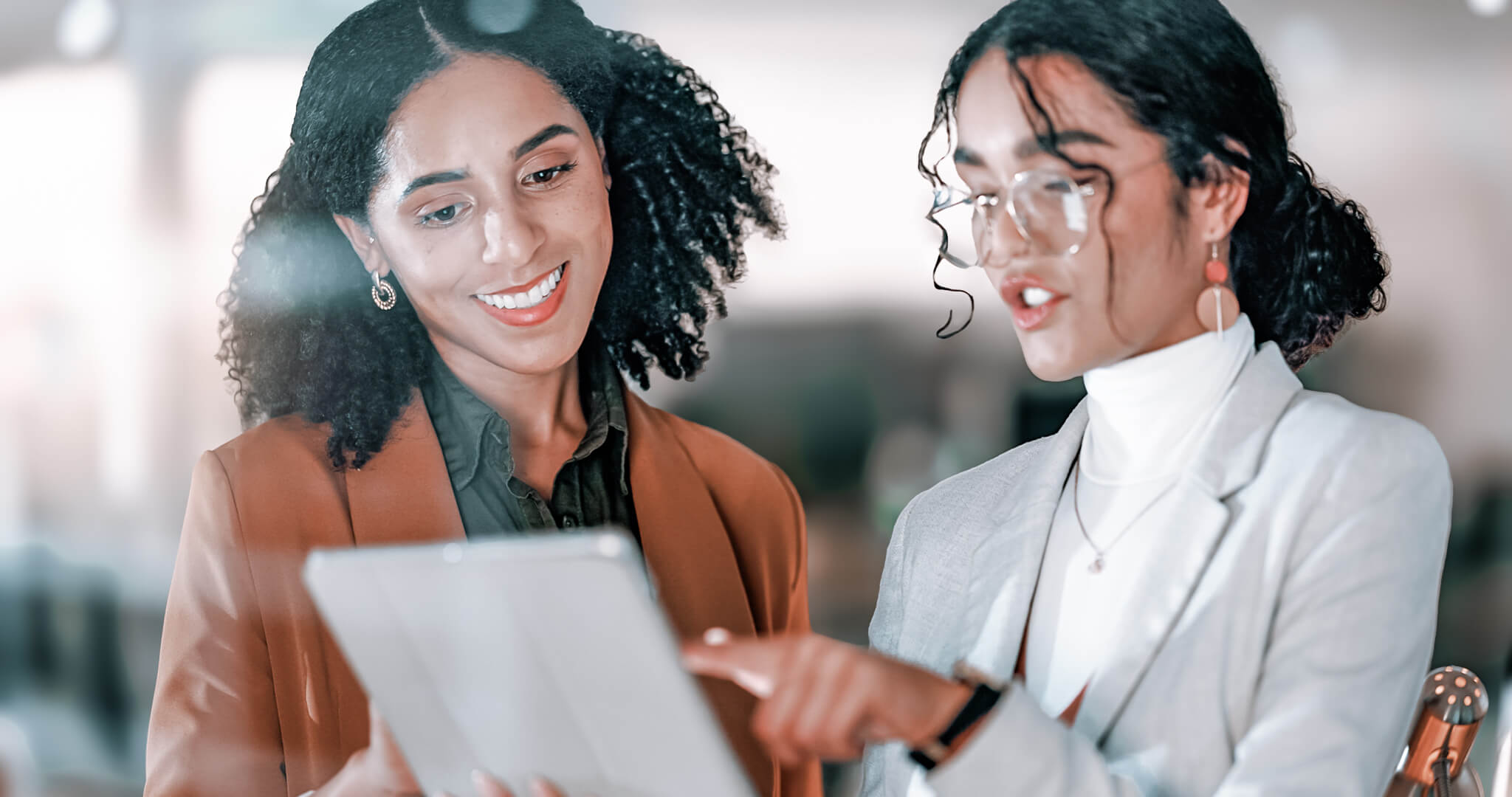 Two female SEO experts examine a performance report on a tablet