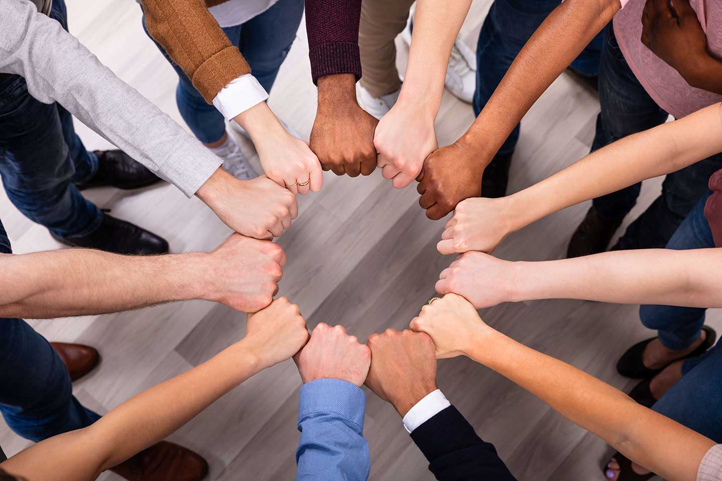 a diverse group of people's arms and hands forming a circle