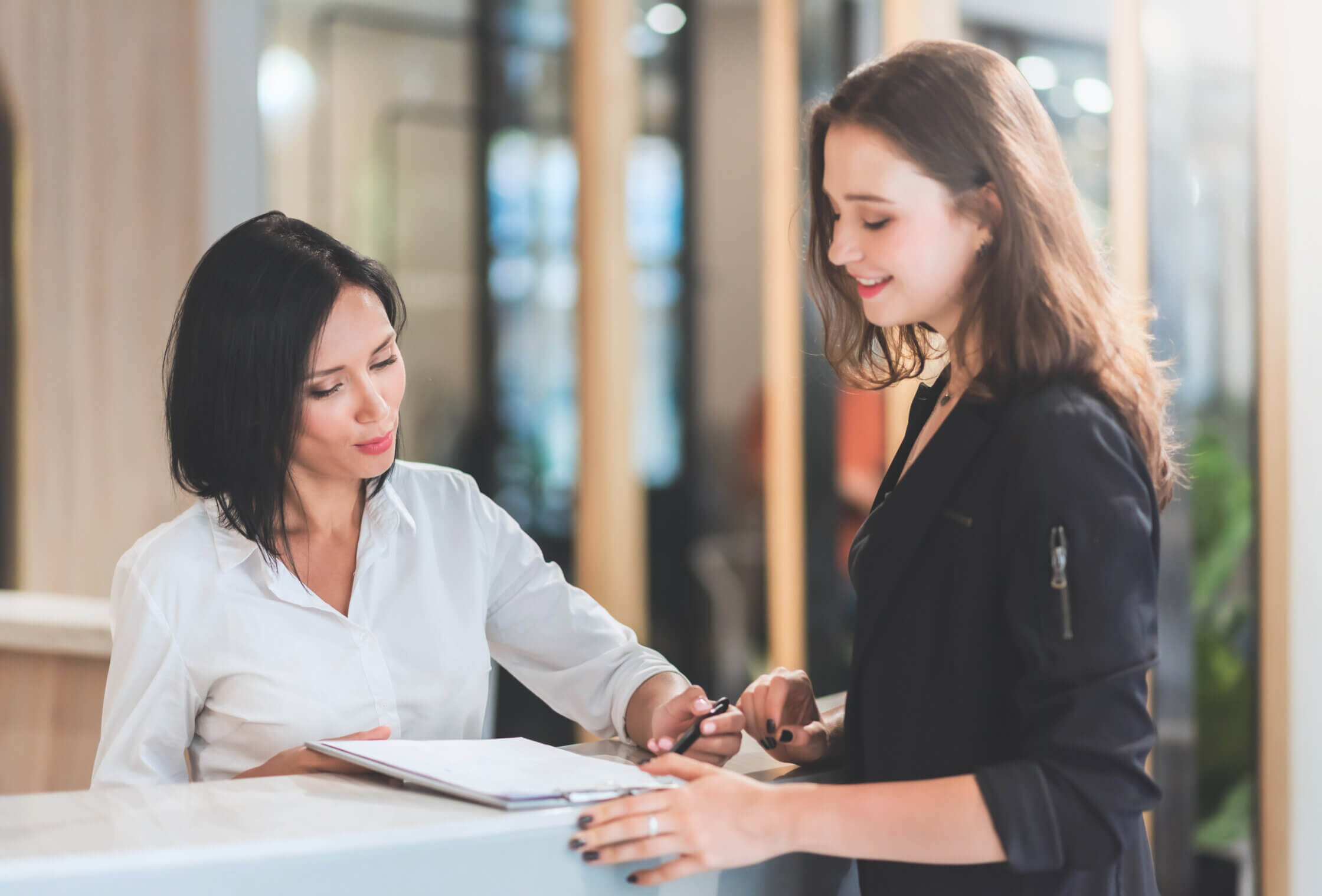 Receptionist woman showing rates of their services to female client at reception