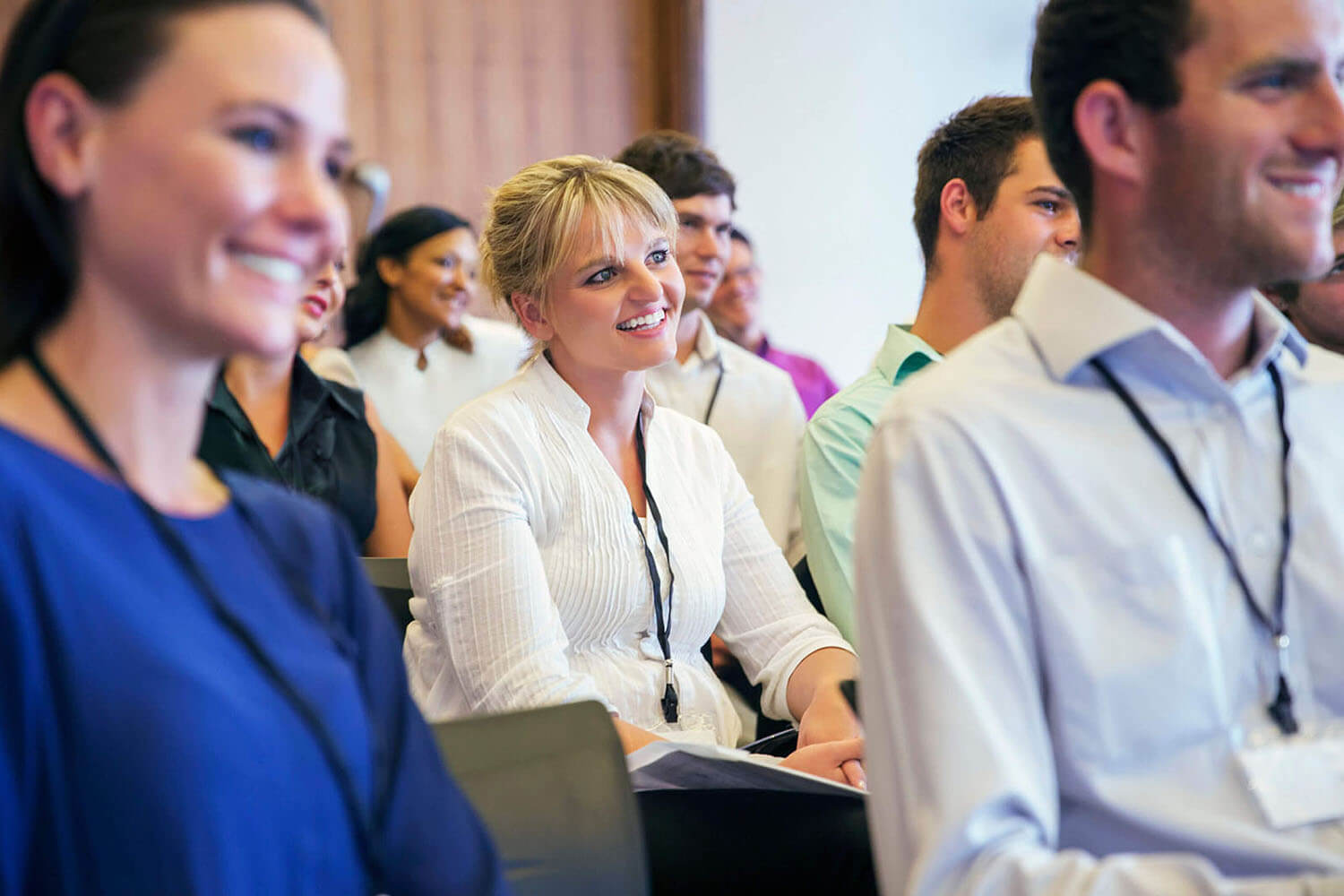 Portrait of smiling woman sitting in conference room, with man and woman in blurred foreground