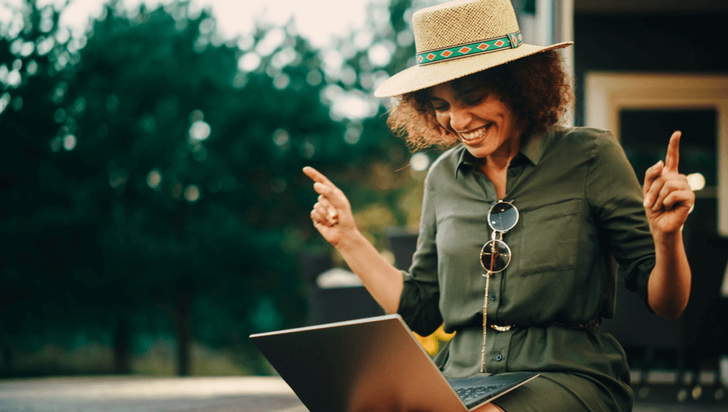 woman in a hat pointing fingers while looking at a laptop