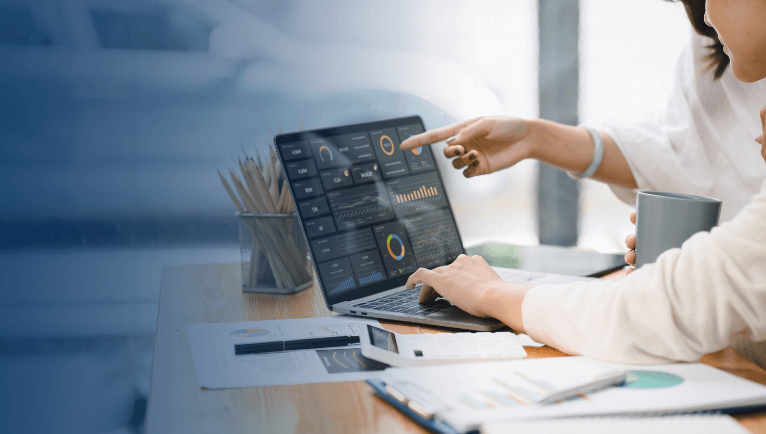 two people looking at charts on a laptop