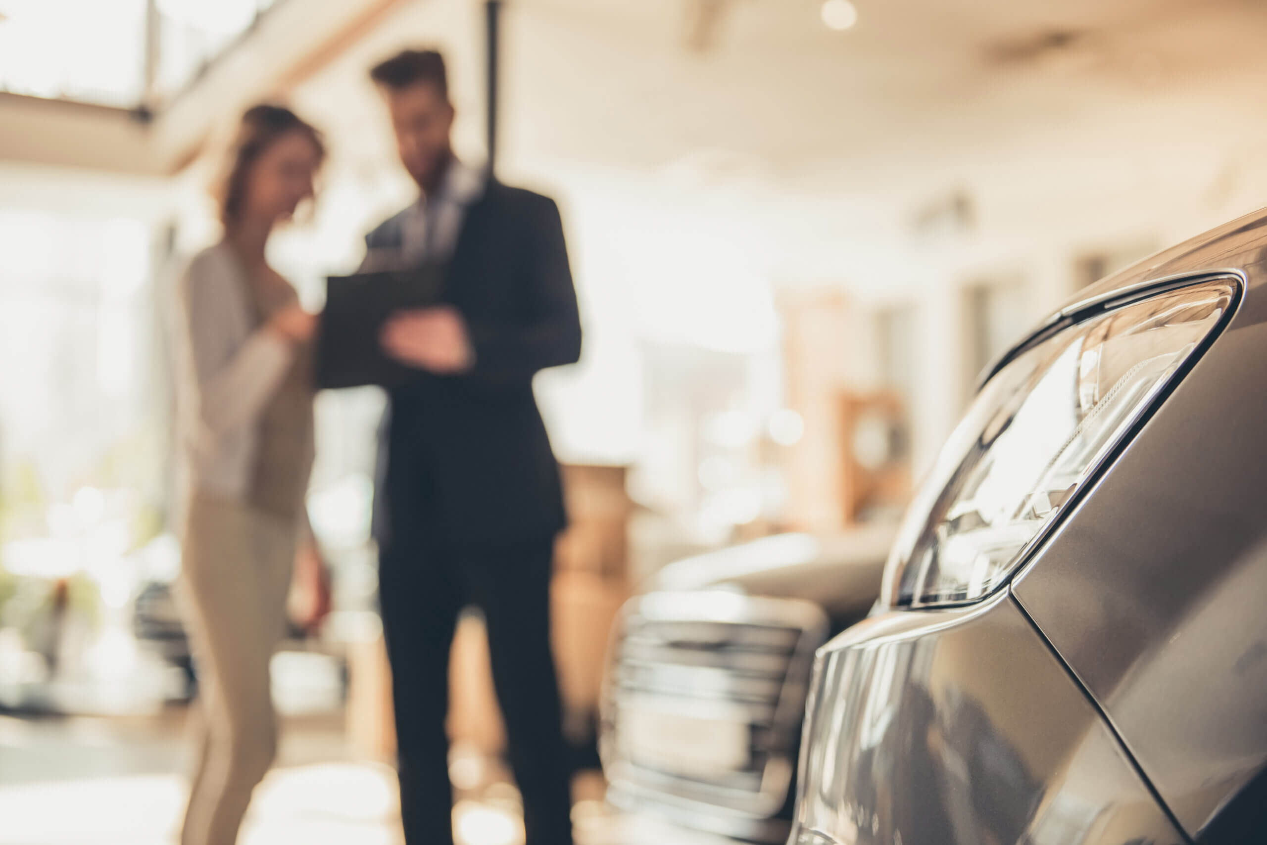 A dealership salesperson engages female customer in a conversation at a dealership showroom.