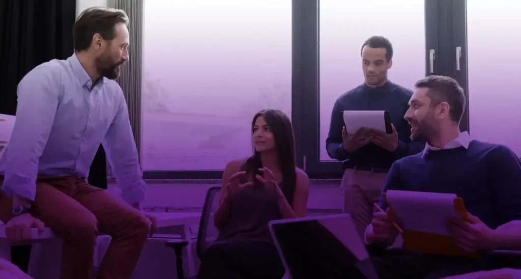 group of people at work having conversation in a windowed office setting