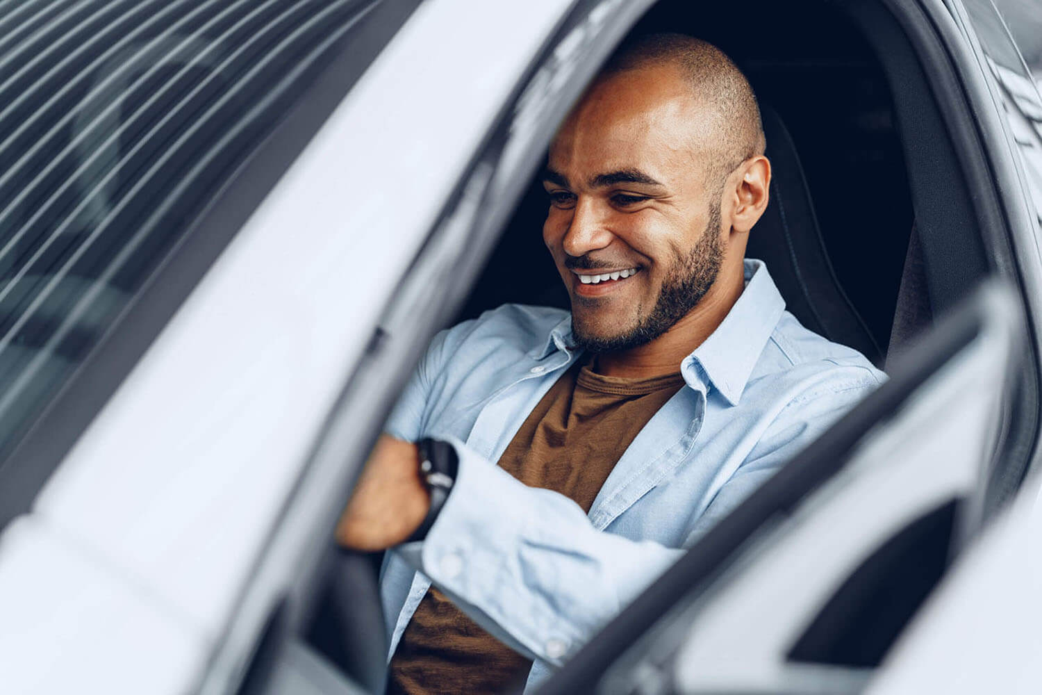 Man smiles as he test drives a vehicle in a dealer showroom