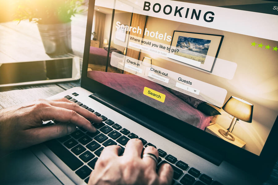 person's hands on laptop keyboard with hotel booking website open